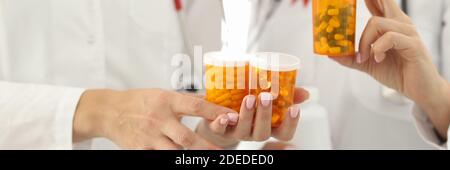 Doctors with red ribbon on uniforms are holding jars of medicines closeup Stock Photo