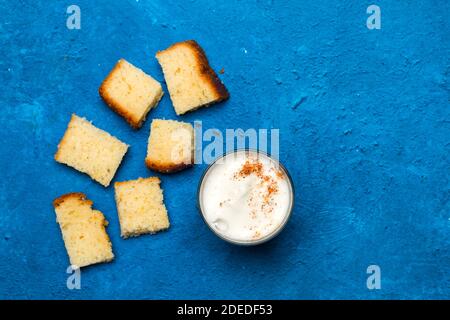 Pieces of vanilla cake and a glass of cappuccino on a classic blue background Stock Photo