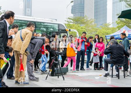 A Chinese man watching his camera and recording a man playing Chinese traditional musical instument Erhu in Shenzhen, China Stock Photo