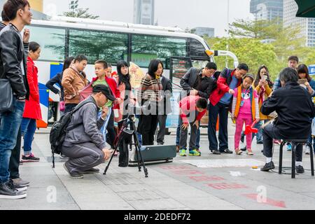 A Chinese man watching his camera and recording a man playing Chinese traditional musical instument Erhu in Shenzhen, China Stock Photo