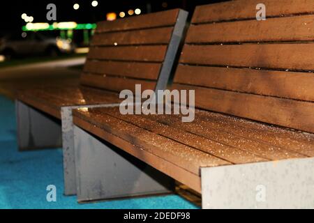 Wooden benches in the yard covered with frost at night Stock Photo