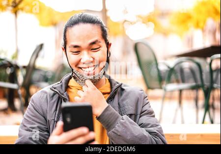 Happy asian guy smiling with open face mask after lockdown reopening - New normal lifestyle concept by confident young man watching news Stock Photo