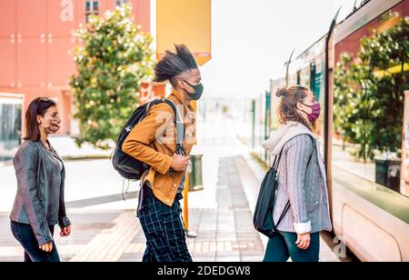 Young people waiting in line practising social distancing at bus city station - New normal transport concept with people wearing face mask on queue Stock Photo