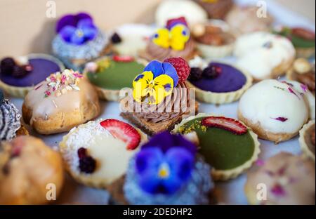 Selection of colorful and delicious cake desserts in box on table. Stock Photo