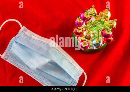 Mini Christmas tree next to a blue facemask, top view. Christmas in the covod-19 era concept photo. Stock Photo