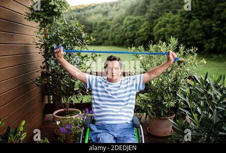 Senior man in wheelchair doing exercise on terrace. Stock Photo