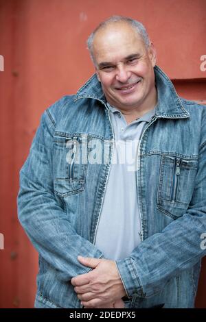 An elderly man in a denim jacket looks at the camera and smiles. An upright fifty-year-old gray-haired man of large build. Stock Photo