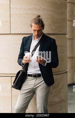 Handsome man with takeaway coffee using smartphone in the city Stock Photo