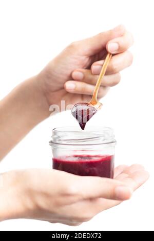 Woman hand holding a spoon with berry jam in jar in clipping path. Stock Photo