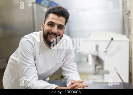 Portrait of young pastry chef looking at camera smiling. Stock Photo