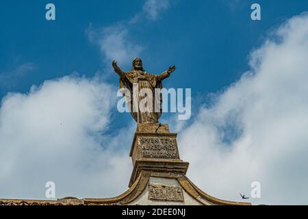 Outer view of the church of Diano showing a large statue of Jesus Christ on the roof top - City of Diano, Italy, Piedmont Stock Photo
