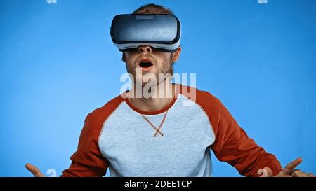 shocked young man in virtual reality headset on blue Stock Photo