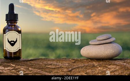 Natural beard Oil -  barbershop product photography and balance stones.Beard oil in amber bottle - stacked on green nature background. Stock Photo