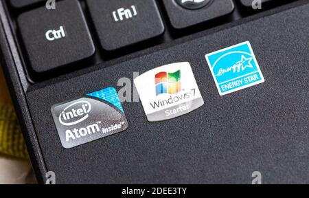 Stickers, manufacturer production labels on a laptop palmrest closeup. Windows 7 Starter logo, Intel Atom, Energy Star symbols macro, detail shot, old Stock Photo