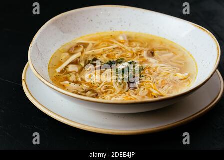 chicken broth with noodles on a textured black background Stock Photo