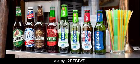 Simple row of Polish beer bottles, set, various brands, many different alcohol bottles and plastic straws. Żubr, Leżajsk, Dębowe, Lech, Redds, 0% beer Stock Photo