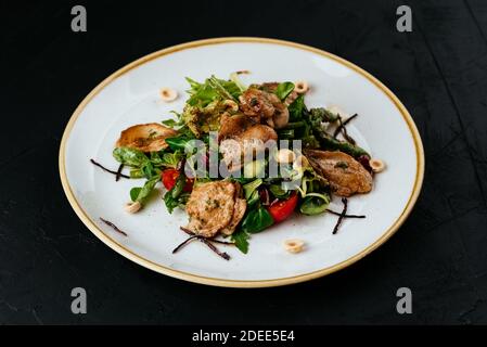 warm salad with grilled quail on a black background Stock Photo