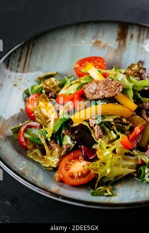 warm salad with marbled beef steak on a black background Stock Photo