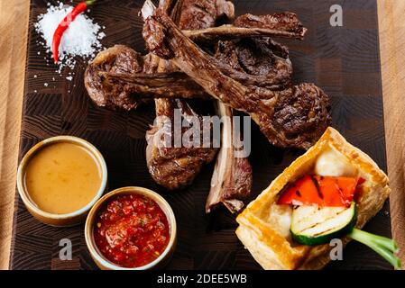grilled lamb rack with vegetables and sauce on a black background Stock Photo
