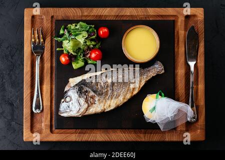grilled Dorado with vegetables on a black background Stock Photo