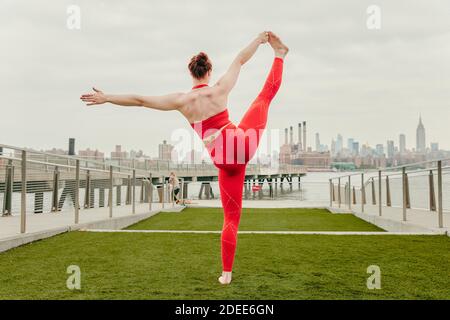 Young female athlete stretching by waterfront in Brooklyn, NY. Stock Photo