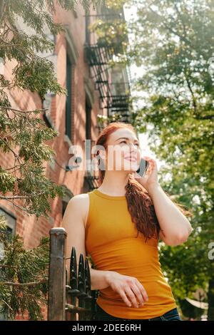 Young woman happily talking on phone outdoors  in Brooklyn street. Stock Photo