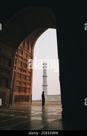 Young woman looking at Taj Mahal from inside Kau Ban Mosque during sunrise, Agra, India Stock Photo