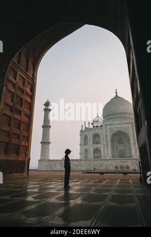 Young woman looking at Taj Mahal from inside Kau Ban Mosque during sunrise, Agra, India Stock Photo