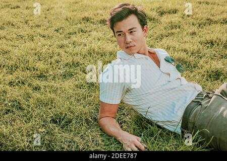 Portrait of a young man sitting on grass. Stock Photo