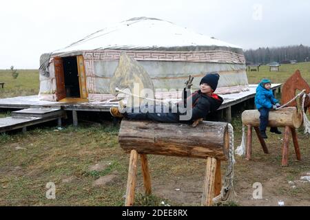 Children sitting on wooden horses in front of Yakut yurt Stock Photo