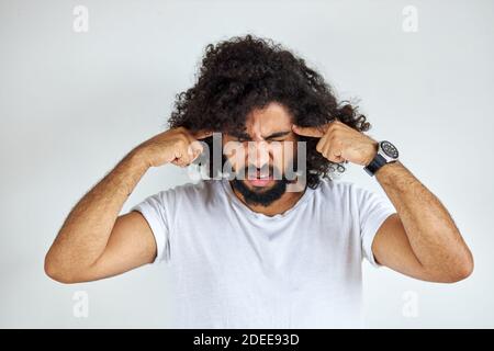 handsome arabian man with beard is suffering from headache desperate and stressed because pain and migraine. hands on head. isolated over white backgr Stock Photo