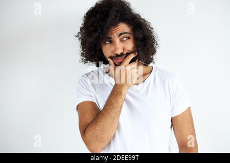 portrait of thoughtful young arabic arabian male isolated in studio, curly dark haired male is thinking about question, pensive expression. doubt conc Stock Photo