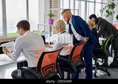 friendly team of diverse colleagues coworking in the office, people in formal wear sit discussing projects and ideas Stock Photo