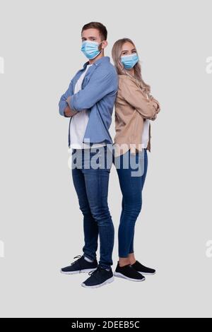 Couple Standing Back to Back Wearing Medical Mask Watching to Camera. Man and Woman, Lovers, Friends, Couple Concept Stock Photo