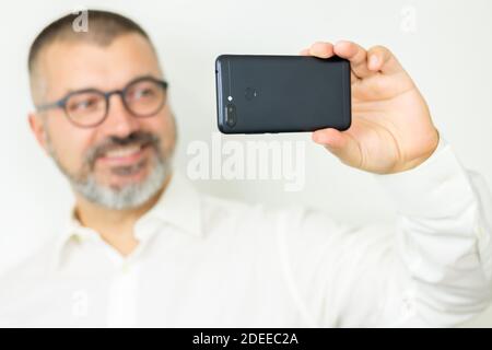 Handsome bearded man wearint shirt and glasses taking selfie or communicates online Stock Photo