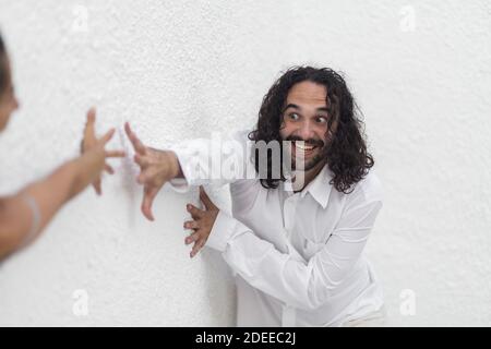 A young Hispanic bearded man with long hair trying to hold her girlfriend's hand Stock Photo