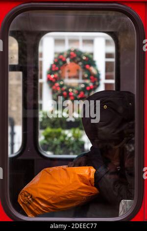 London, UK. 30th Nov, 2020. A large wreath on an estate agents window behind a homeless person asleep on the back of a bus - Closed retailers do their best to promote Christmas sales. People are still out in central london, and prepare to re-open as the second lockdown nears its end. The Christmas lights are on but the shops are shut. Many people wear masks, even outside. Credit: Guy Bell/Ģ����ý Live News Stock Photo