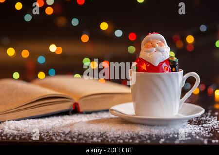 A ceramic figurine of Santa Claus sits in a white cup. Stock Photo