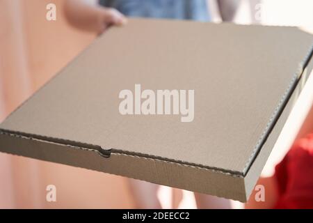 a square cardboard pizza box in the hands of a girl Stock Photo
