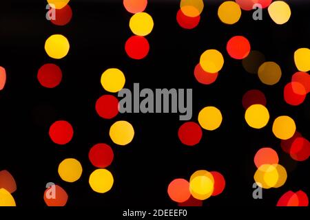 Red and orange bokeh from glowing garlands on a black background. Stock Photo