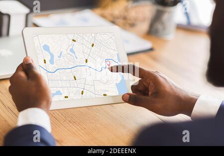 Unrecognizable Black Businessman Using Taxi Services App On Digital Tablet In Office Stock Photo