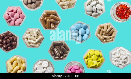 Various medical capsules and pills in hexagonal jars on blue background Stock Photo