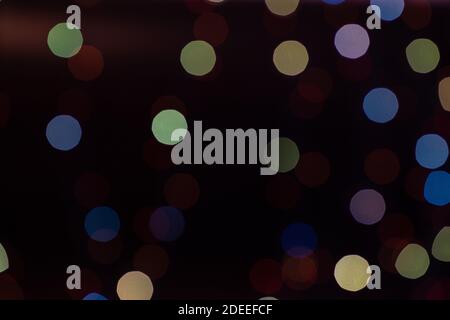 Multicolored bokeh from glowing garlands on a black background. Stock Photo