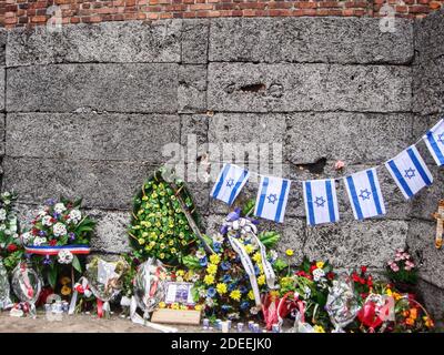 Flowers and wreaths lay at The Death Wall at the Auschwitz Concentration and Exteerminaton Camp. Located in the yard at the side of Block 11 Stock Photo