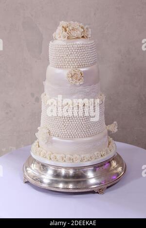 Off-white cream or ivory tiered wedding cake with sugar flowers Stock Photo