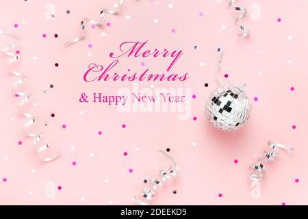 Text Merry Christmas and Happy New Year on pink background with silver disco ball Stock Photo