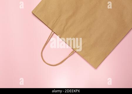 Minimal flate lay. Empty kraft paper bag on pink background with copy space. Waste free concept. Stock Photo