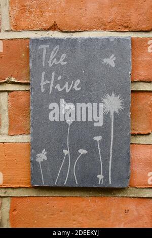 Slate bee hive artwork sign with 'The Hive' writing and flowers and bumblebees. Stock Photo