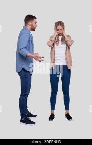 Couple Having a Fight. Man Screaming at Girl. Man is not Satisfied. Couple Standing Isolated. Girl Closing Eyers Stock Photo