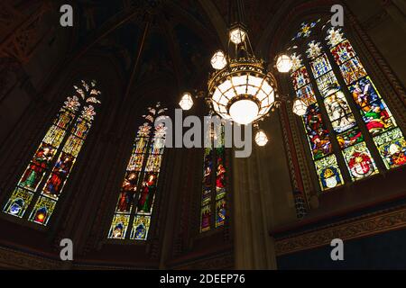 Geneva, Switzerland - November 26, 2016: St. Pierre Cathedral interior fragment with stained glass windows and chandelier. It was built as a Roman Cat Stock Photo